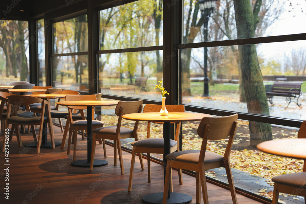 Fototapeta premium Stylish restaurant with large windows and comfortable furniture. Interior design