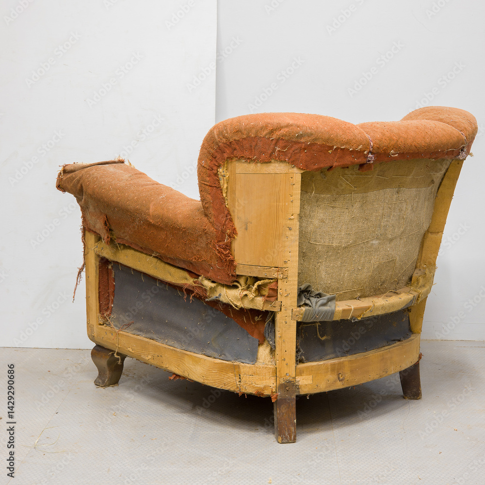 Old and damaged orange couch with exposed wood frame in an indoor setting showcasing its worn condition
