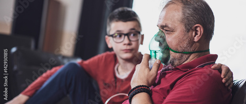 Middle-aged man using oxygen mask at home for breathing treatment