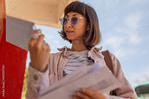 Photography Close up of woman looking through envelopes standing near mailbox