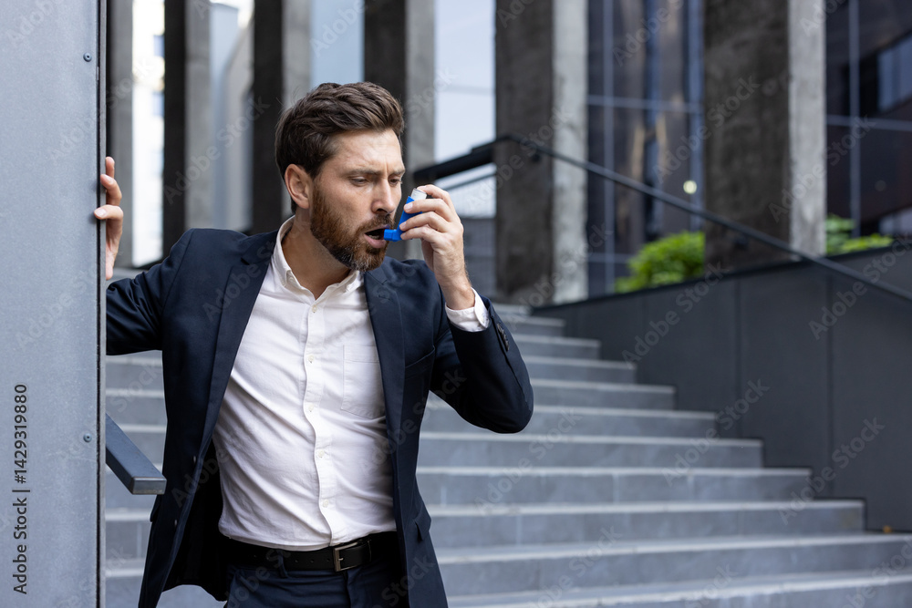 A professional man uses an inhaler outside of a modern office building. He appears to be struggling with a sudden asthma attack or breathing problem while on the stairs.
