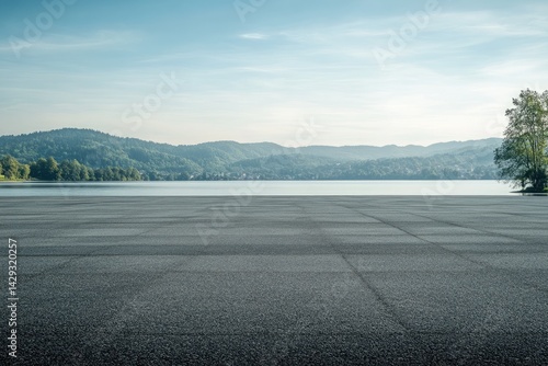 Fototapeta Naklejka Na Ścianę i Meble -  Empty paved area by a serene lake with hills