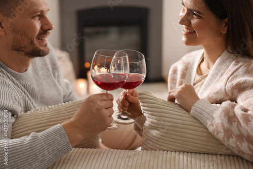 Obraz na płótnie Happy couple clinking glasses of wine on sofa in room with stylish fireplace w salonie