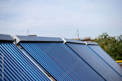 А solar water heating collectors, equipped with blue vacuum tubes, are installed on a rooftop to harness solar energy, converting it into heat for domestic heating and  hot water systems