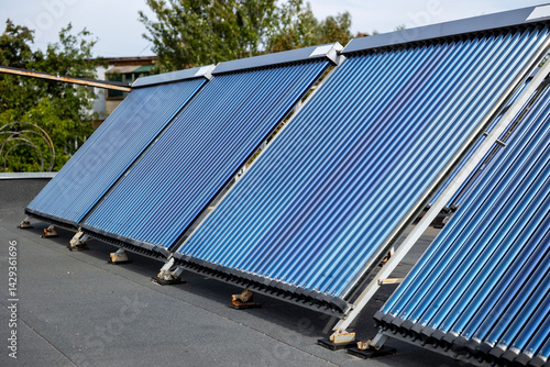 А solar water heating collectors, equipped with blue vacuum tubes, are installed on a rooftop to harness solar energy, converting it into heat for domestic heating and  hot water systems