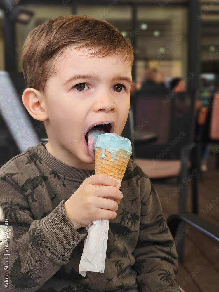 Cute toddler boy eating a blue ice cream in a waffle cone. Cute toddler boy eating a blue ice cream in a waffle cone.