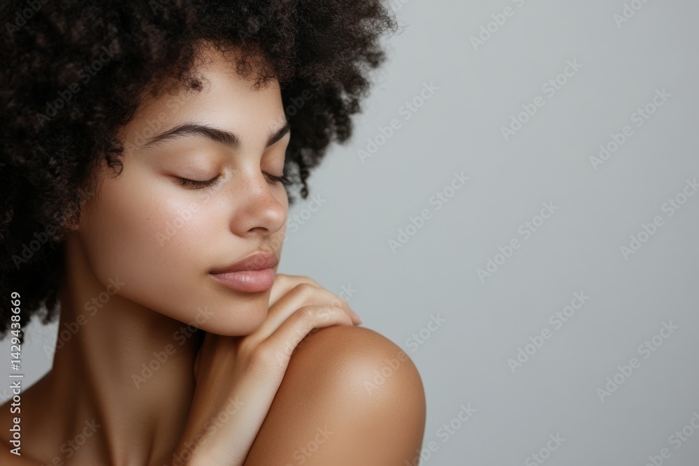 Serene portrait of a young woman with curly hair, eyes closed, and a peaceful expression against a neutral background. Serene portrait of a young woman with curly hair, eyes closed, and a peaceful expression against a neutral background.