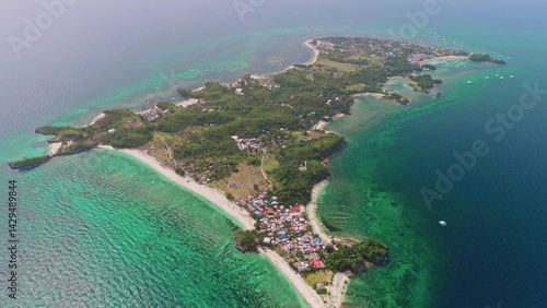 Aerial view of Malapascua Island in the Philippines, featuring vibrant turquoise waters, lush tropical vegetation, and colorful houses along the picturesque coastline