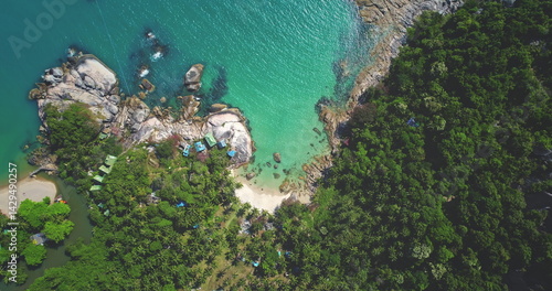 Capturing breathtaking aerial views of a tropical island with crystal-clear turquoise waters lapping against a pristine white sand beach, surrounded by lush greenery