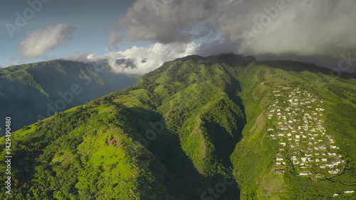 Obraz na płótnie Aerial view of a tropical island with houses nestled on the slopes of a lush green mountain, showcasing the beauty of nature and human settlement. Remote wild nature paradise, exotic summer travel w salonie