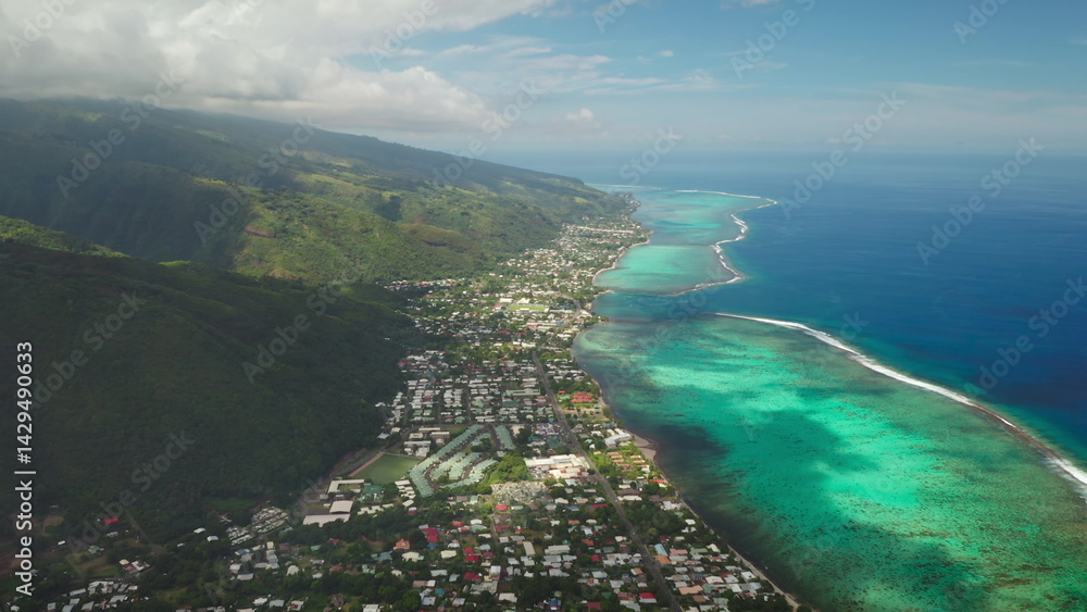 Capturing stunning aerial views of a tropical coastline where lush green mountains meet vibrant turquoise waters, revealing a picturesque town nestled in nature's beauty