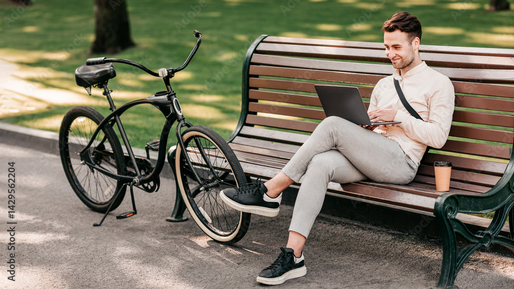A young man sits relaxed on a park bench, typing on his laptop. Next to him, a bike leans against the bench while a coffee cup sits on the ground, capturing a calm lifestyle moment. A young man sits relaxed on a park bench, typing on his laptop. Next to him, a bike leans against the bench while a coffee cup sits on the ground, capturing a calm lifestyle moment.