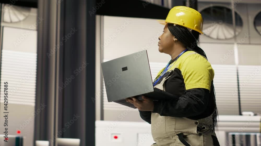 Smart factory mechanic computerizing operations and monitoring energy consumption using laptop. Repairman walking in industry 4.0 plant with notebook, providing technical support, camera B Smart factory mechanic computerizing operations and monitoring energy consumption using laptop. Repairman walking in industry 4.0 plant with notebook, providing technical support, camera B