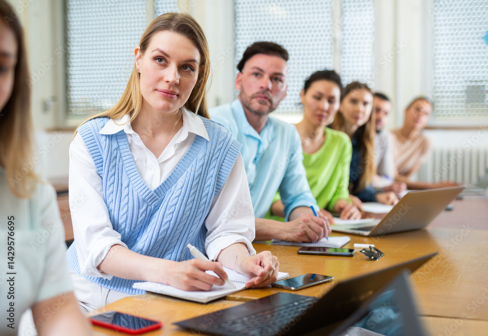 Fototapeta premium Female senior student listening lecture in class room. Students sitting in row.