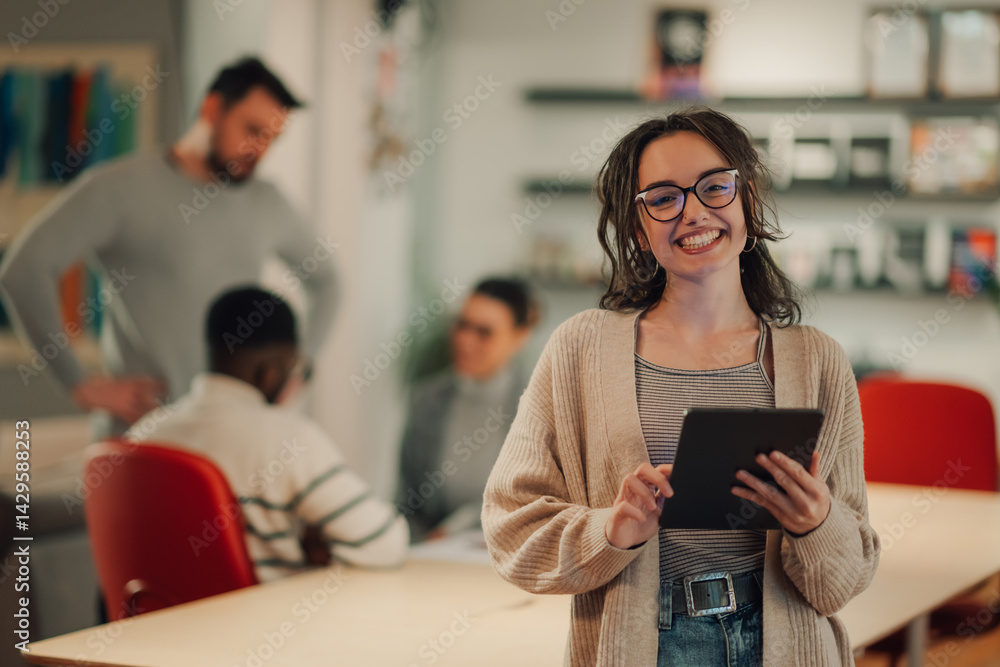 Fototapeta premium Young businesswoman smiling and using digital tablet in modern office