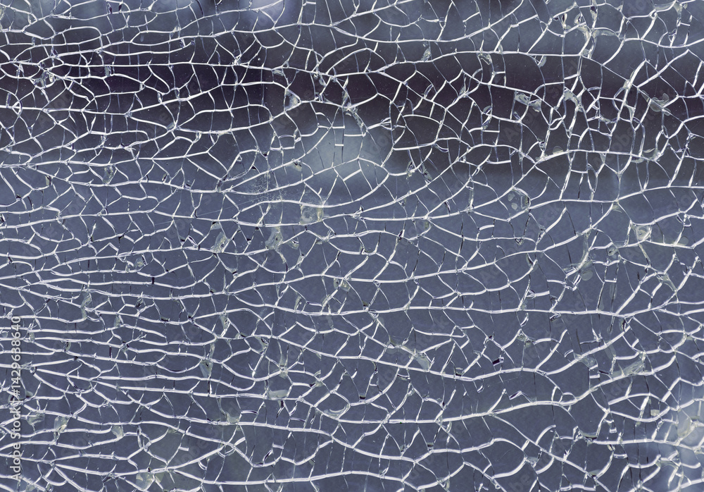 Detail of broken tempered glass pane too many small irregular shape pieces holding together. Texture of cracked broken glass cracked by impact, Cracks on the glass surface background, Copy space.