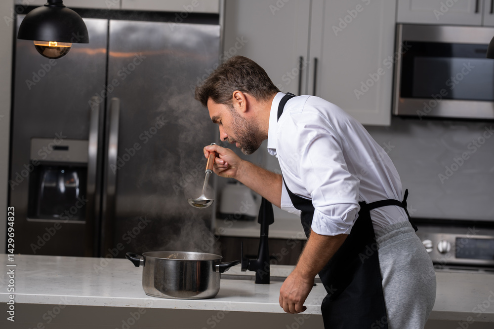 chef stirring a pot of aromatic soup with ladle. Chef cook in uniform cooking soup in the big cooker at the restaurant kitchen. Man cooking in the kitchen. Handsome chef catching ingredients for soup chef stirring a pot of aromatic soup with ladle. Chef cook in uniform cooking soup in the big cooker at the restaurant kitchen. Man cooking in the kitchen. Handsome chef catching ingredients for soup