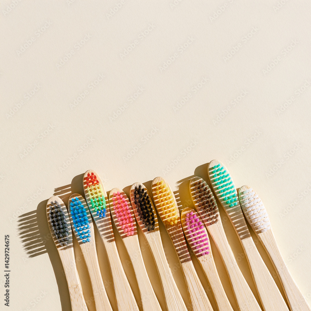 Eco friendly Bamboo toothbrushes with colored bristles at sunlight with dark shadows on beige background. Sustainable living concepts, minimal style aesthetic photo, top view set wooden brushes