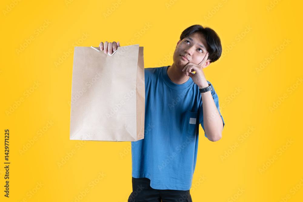 a man showing his brown shopping bag while thinking a man showing his brown shopping bag while thinking