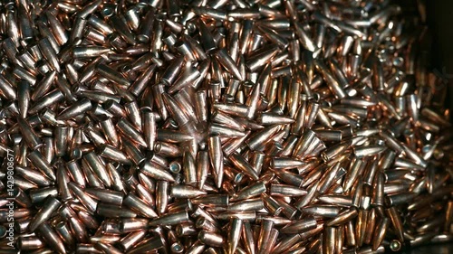 Shiny bullets fall down onto pile at manufacturing plant