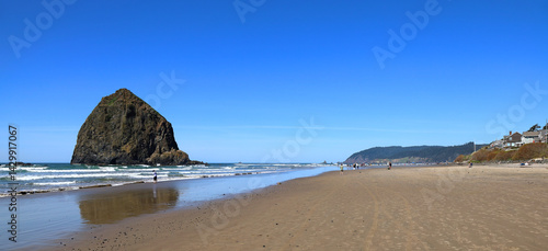 Panoramic view of the iconic Haystack Rock and Cannon Beach in Oregon on a clear sunny day.