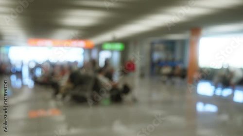Defocused indoor airport view with blurred travelers in background surrounded by bright signage and modern architectural details
