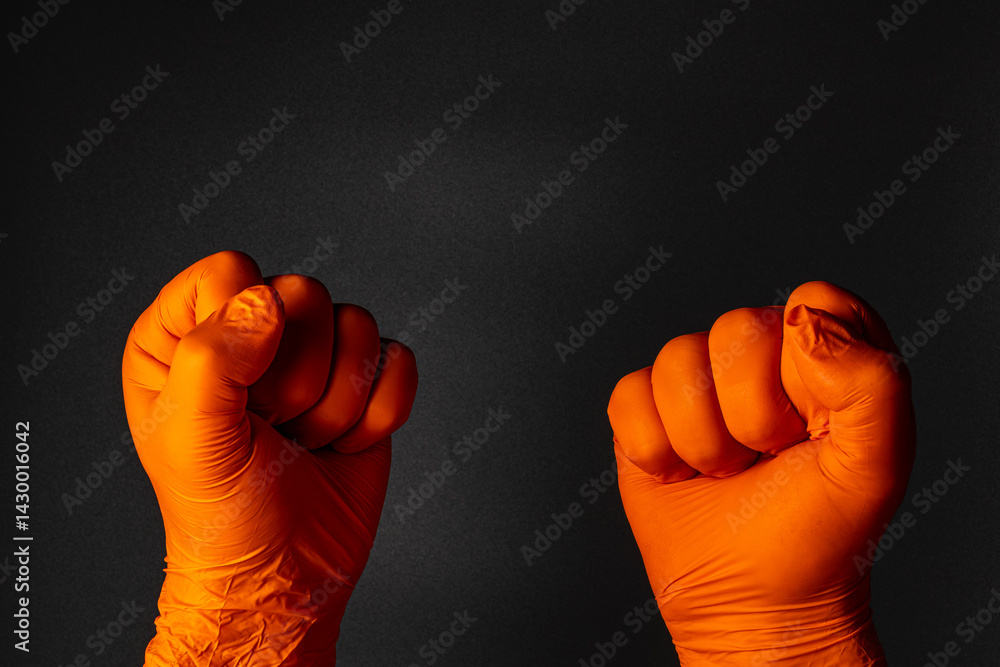 Hands in orange gloves raised in solidarity during protest