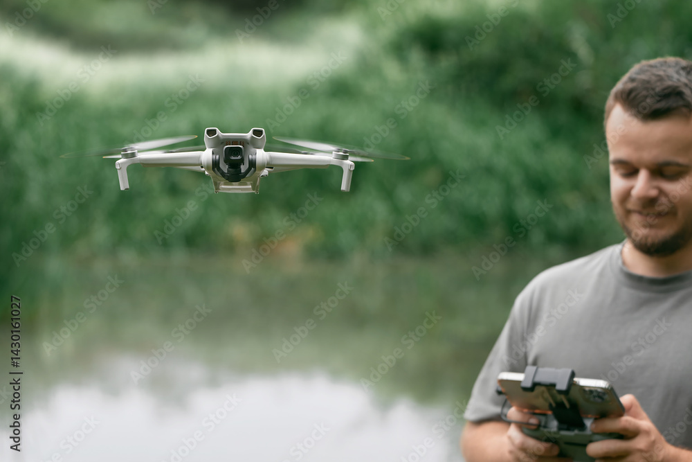 Man controlling drone with controller by water