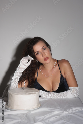 An elegant woman in a black dress celebrates her birthday with a cake and candle. This high-quality image is ideal for promoting luxury, special events, and sophisticated celebrations in lifestyle and