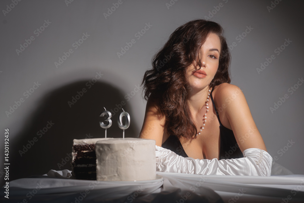 A glamorous woman in an evening dress and white gloves celebrates her 30th birthday with a cake and candle. This high-quality stock photo is perfect for promoting special occasions, elegance, and