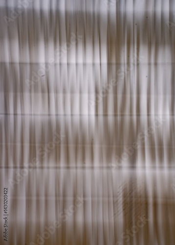 abstract blur monotone background of white or off white curtains in window with light coming in blurred by intentional camera movement and long time exposure making wavy like moving up and down lines