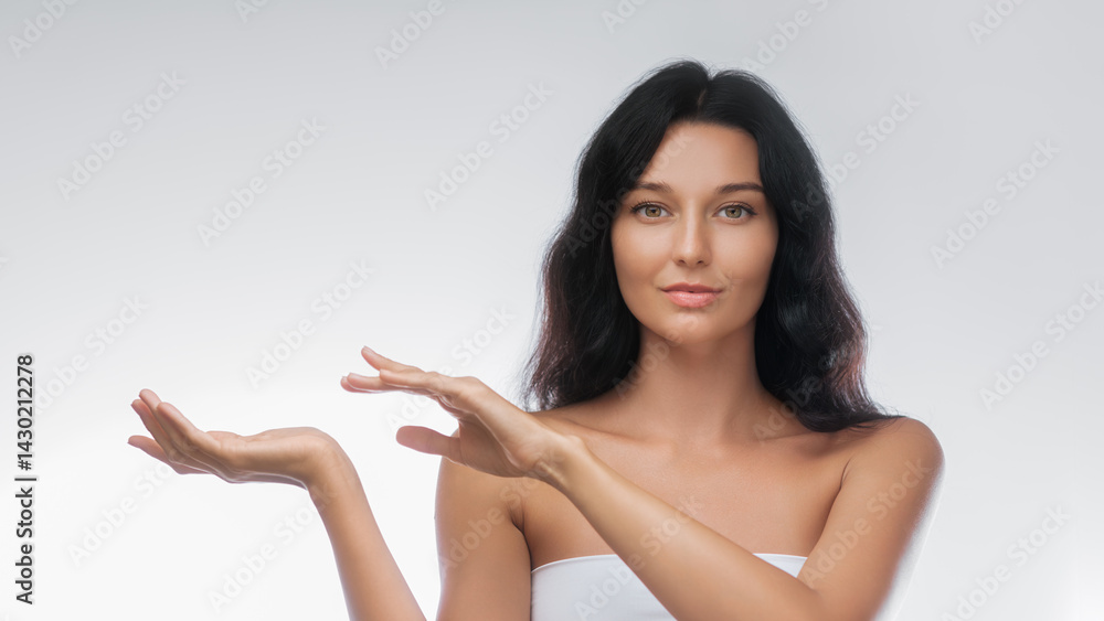 An elegant Asian woman with long black hair gracefully presents an invisible product with poised hands against a neutral background. Perfect for beauty, skincare, and cosmetic advertisements