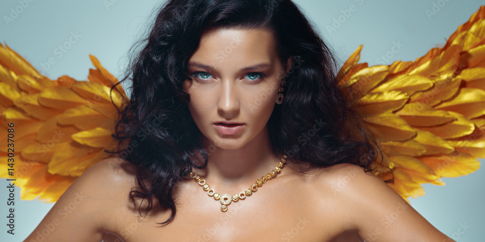 Bold topless woman with glowing skin, golden wings, and elegant jewelry poses confidently in studio. High quality conceptual fashion and fantasy image for luxury promo use.