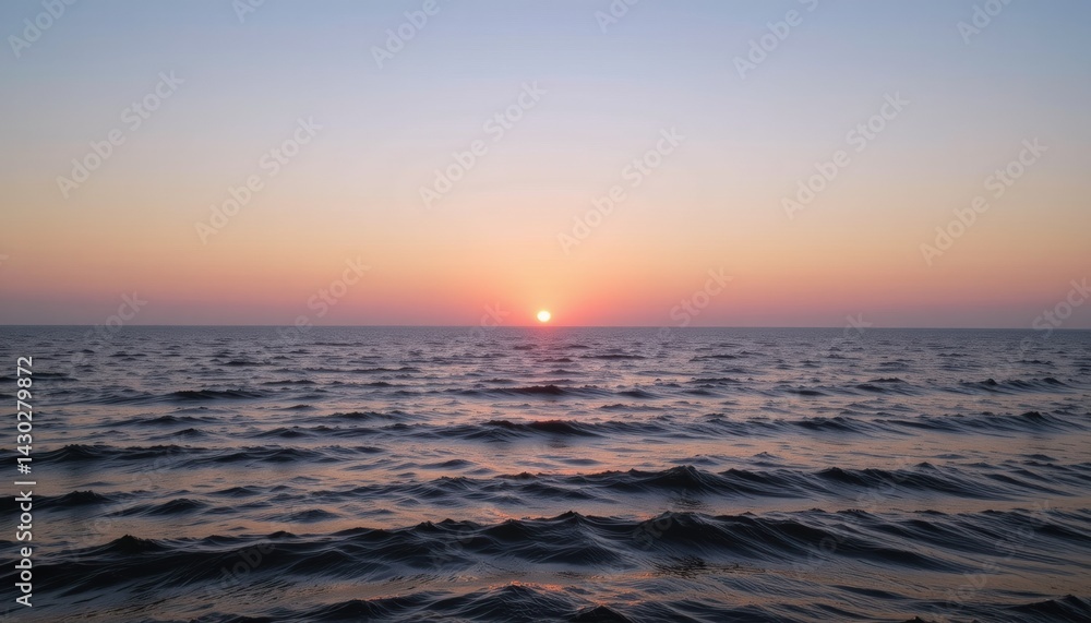 Obraz premium Sunset over calm ocean waters with gentle waves.