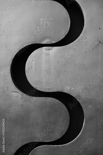 wavy metal cut out of a silver chrome metal wall s shaped shadow in separation of two sides flowing wave in between two parts of thick metallic material rom for type 