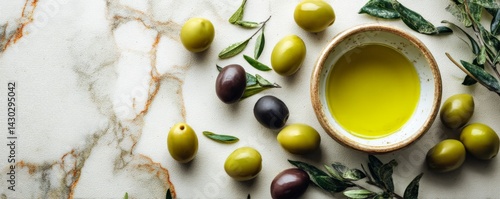 Bowl of olive oil with olives and olive leaves arranged on a light rustic background.