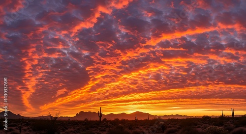 Fototapeta Naklejka Na Ścianę i Meble -  Fiery Arizona Sunset: A breathtaking panorama of a desert sunset with vibrant orange and purple clouds over silhouetted cacti and mountains