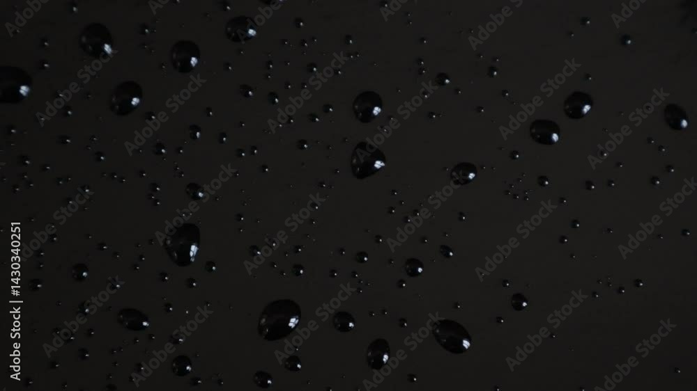 Black water drops on black shiny background