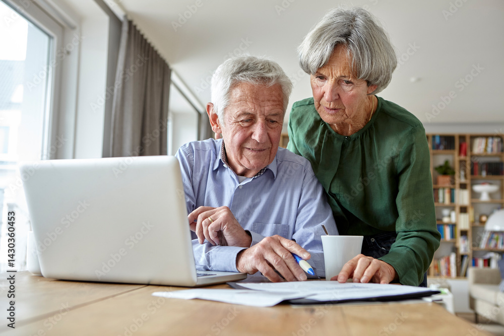 Seniors discussing documents at home with a laptop Seniors discussing documents at home with a laptop