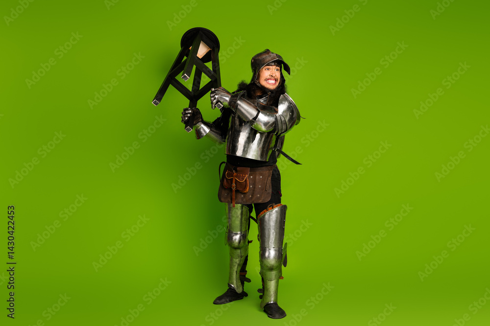 Naklejka premium Young man in medieval knight armor posing against a vibrant green background