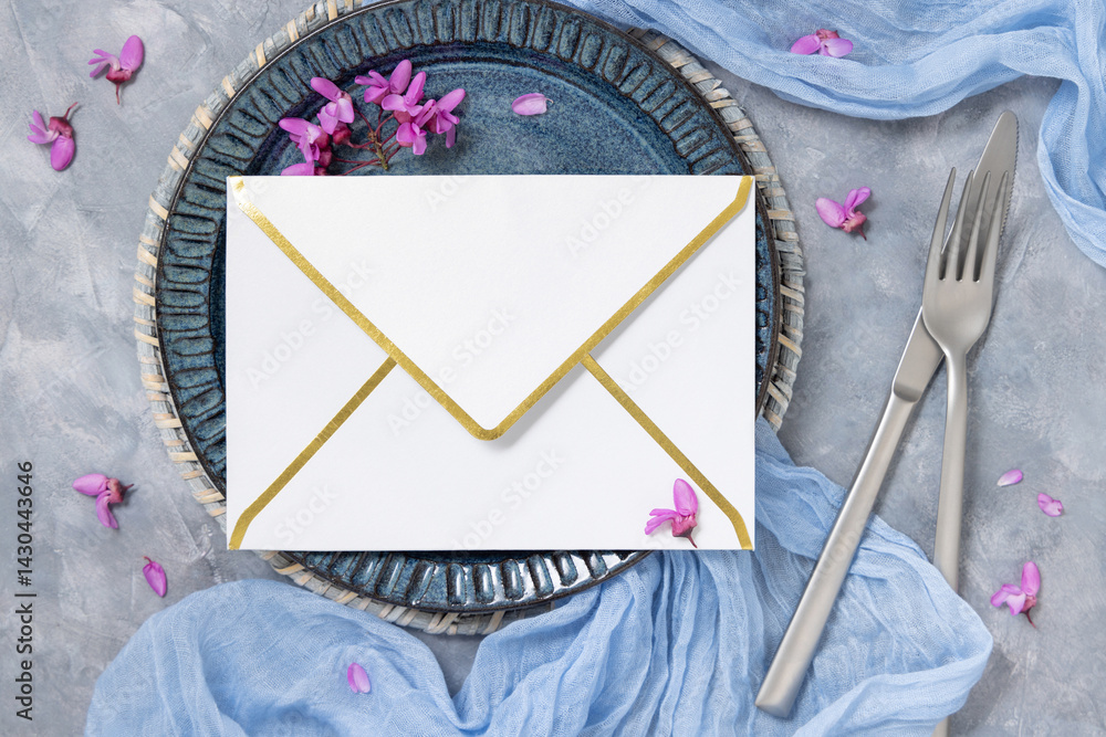 Wedding table place with envelope near fabric and wild purple flowers top view on gray, mockup