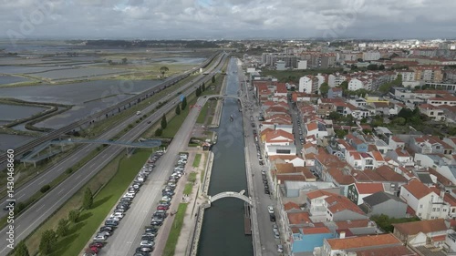 Aerial view of Aveiro city. Drone moving forward over canal Ria de Aveiro with iconic buildings on the right side and Ria de Aveiro on the left side. Cloudy sky on the background.