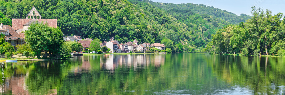 Obraz premium Panorama of the village of Beaulieu-sur-Dordogne and the Dordogne river in Corrèze Nouvelle-Aquitaine in Southern France on a sunny day in summer 