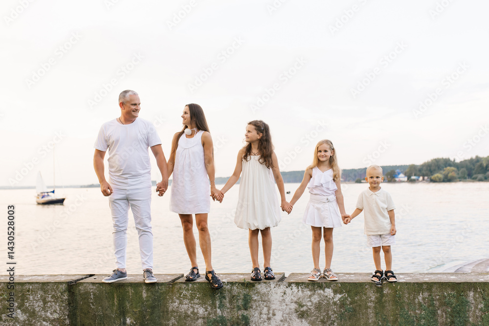 Family of five is standing on pier by the water