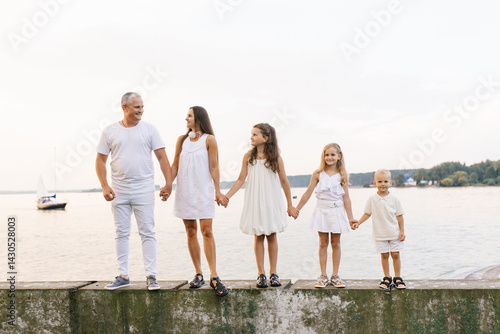 Family of five is standing on pier by the water