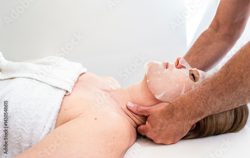 Woman Relaxing with Sheet Mask and Neck Massage at Spa