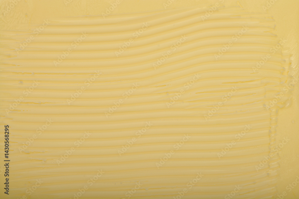 A tightly cropped, top-down shot shows the textured surface of a block of pale yellow butter