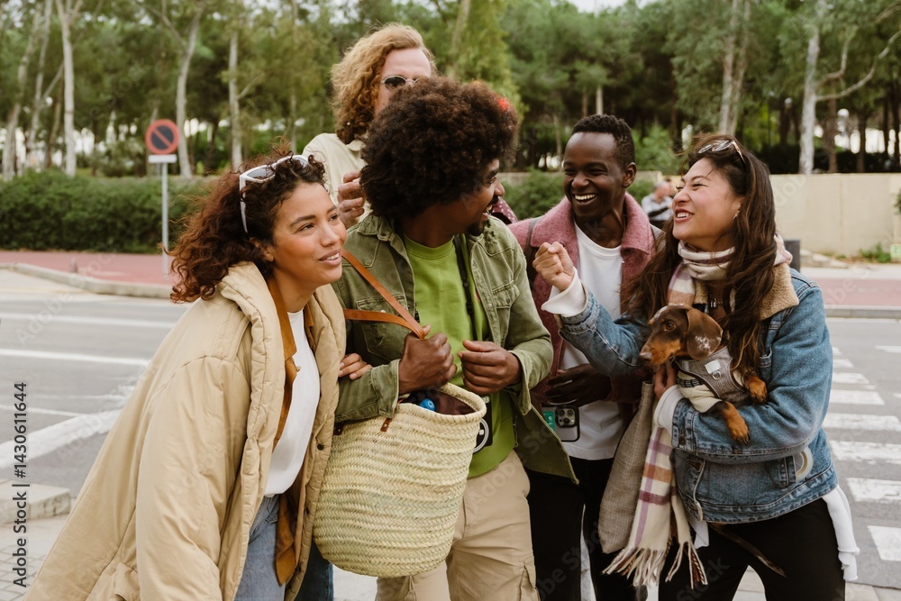 A vibrant group of friends stands laughing together on a city sidewalk, sharing a lighthearted moment. One person holds a small dog, and everyone is dressed warmly in winter jackets. A vibrant group of friends stands laughing together on a city sidewalk, sharing a lighthearted moment. One person holds a small dog, and everyone is dressed warmly in winter jackets.