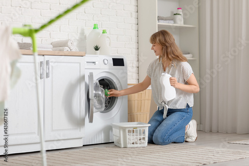 Young woman pouring laundry...