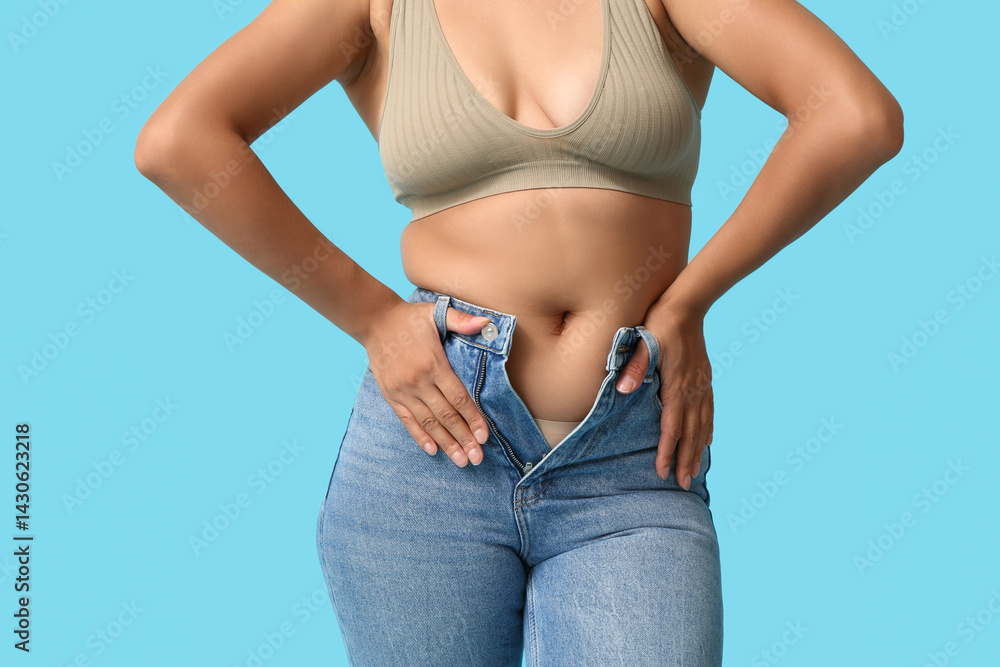 Beautiful young African-American body positive woman in tight jeans on blue background, closeup